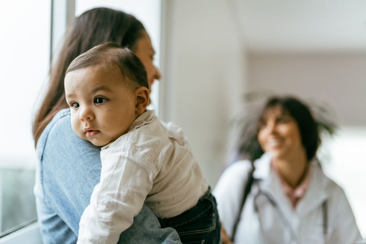 woman holding baby talking to another woman